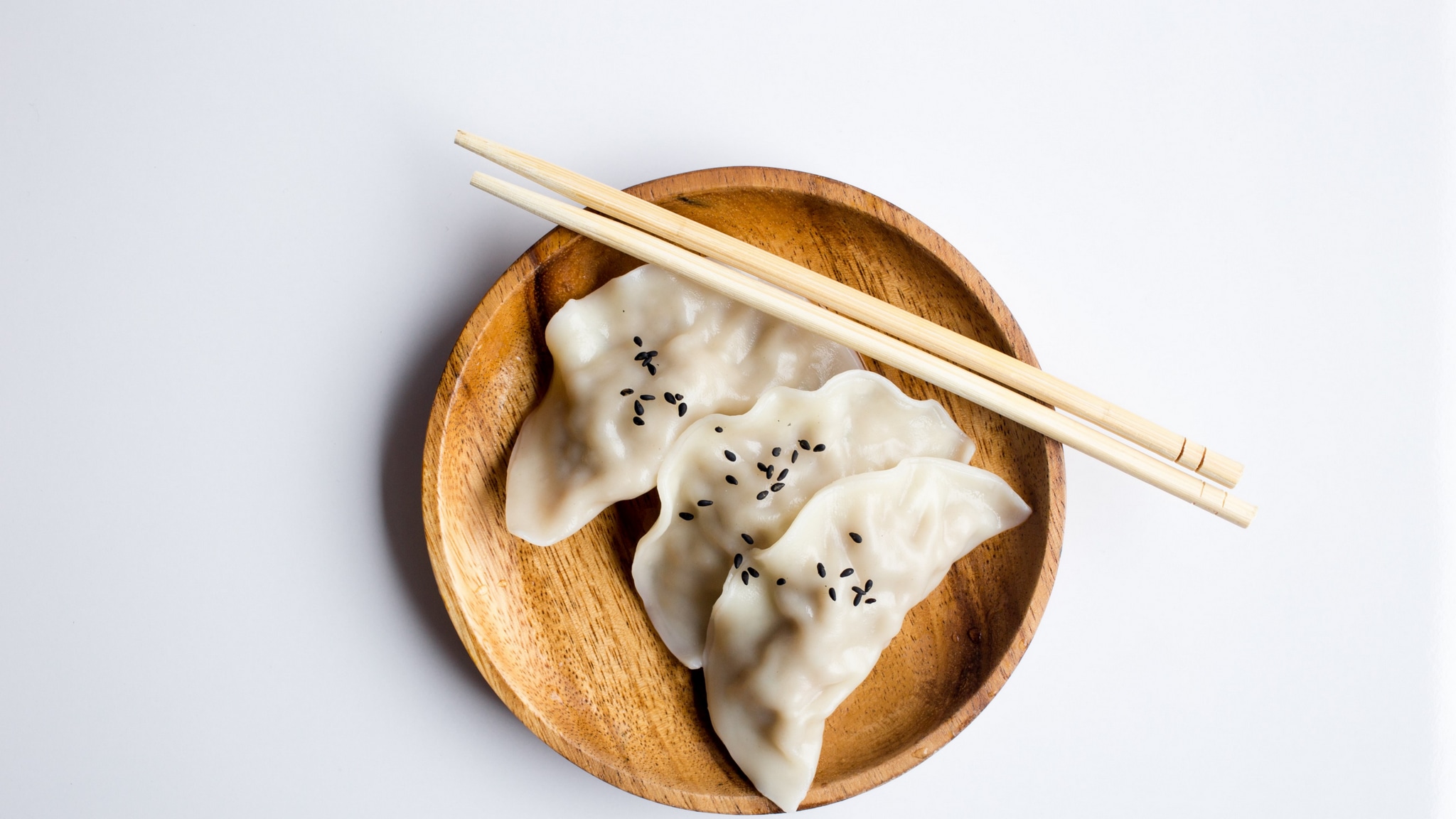 two dumplings on a wood plate with chopsticks